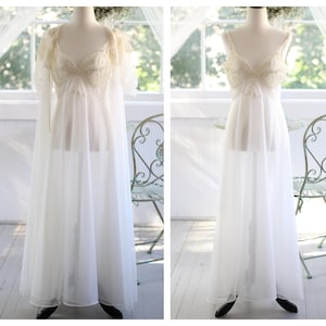 May include: A floor-length white nightgown featuring a sheer bodice with lace detailing and thin straps, paired with a matching sheer robe with short sleeves. The set is displayed on a mannequin, showcasing the layered fabric and delicate texture.