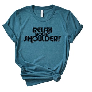 May include: Teal blue t-shirt with the text "Relax Your Shoulders" in a retro font.