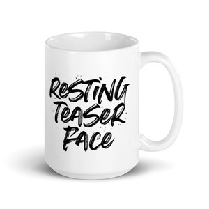 May include: White ceramic mug with black text that reads "Resting Teaser Face".