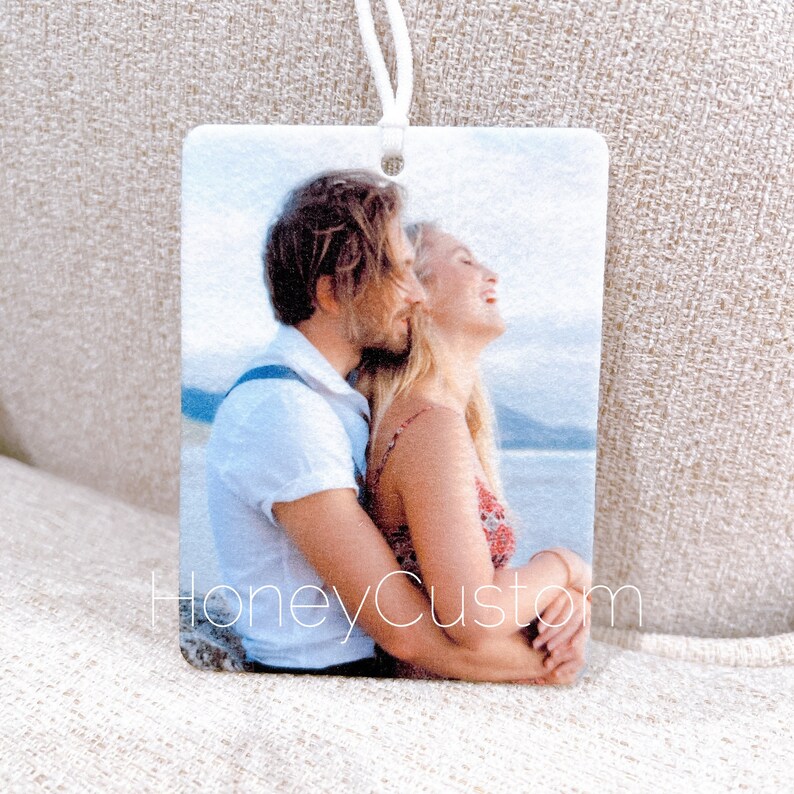 May include: A photo car air freshener with a white background and a photo of a couple hugging. The text "HoneyCustom" is printed on the bottom of the air freshener.