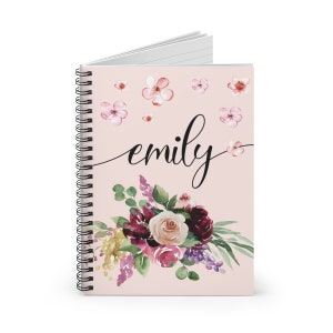 May include: A pink spiral notebook with a floral design and the name "emily" written in black cursive. The flowers are a mix of pink, purple, and burgundy.