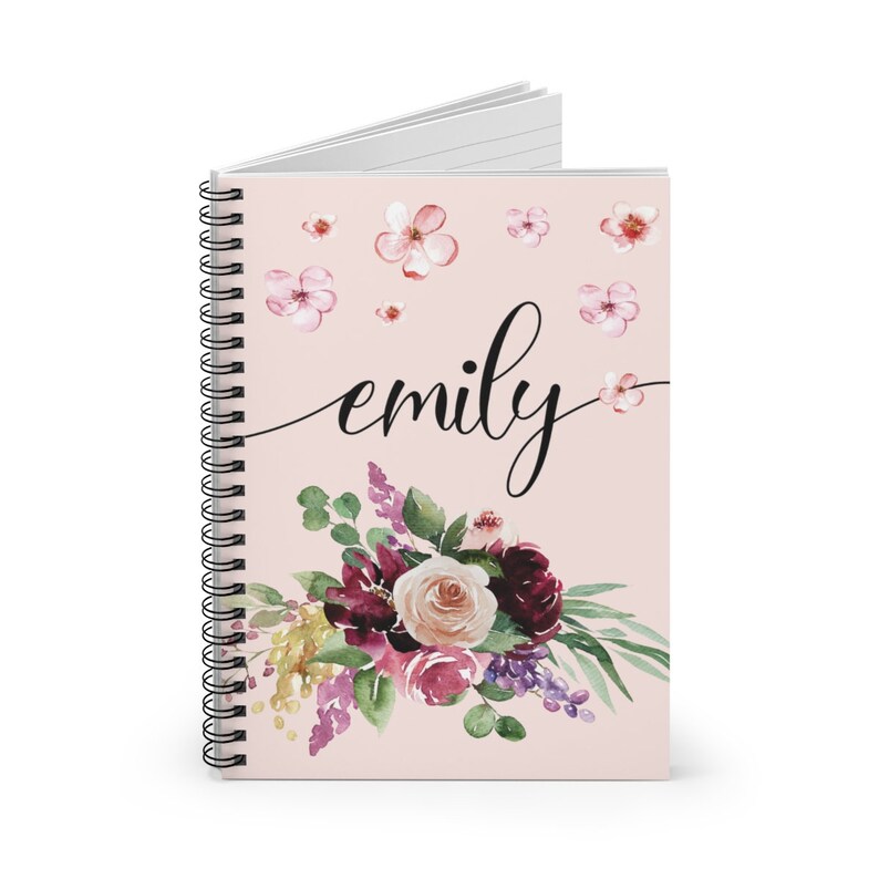 May include: A pink spiral notebook with a floral design and the name "emily" written in black cursive. The flowers are a mix of pink, purple, and burgundy.