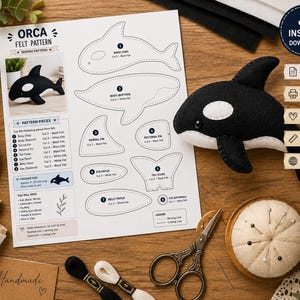 May include: A sewing pattern sheet for a felt orca featuring numbered pattern pieces, a finished orca plush, black and white thread spools, a pincushion with pins, and scissors. The document includes text such as ORCA FELT PATTERN.