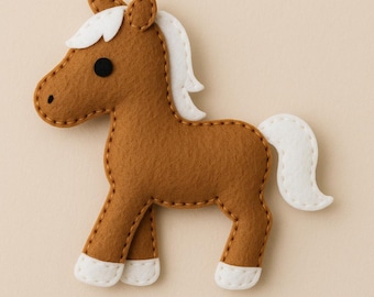 Puede incluir: Un caballo de fieltro marrón con crin, cola y cascos blancos. El caballo tiene un ojo negro y está cosido con hilo marrón. Esta artesanía hecha a mano es una adición encantadora.