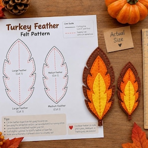Op de afbeelding: Een Turkey Feather viltpatroonblad met instructies, een lijngids en twee afgewerkte viltveren in bruin, oranje en geel. Een houten liniaal toont een schaal van 15 cm en een klein kaartje met het label Actual Size is inbegrepen.