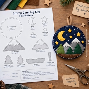 May include: A Starry Camping Sky felt pattern sheet with instructions and a circular felt ornament featuring a yellow moon, yellow stars, gray mountains with white peaks, green pine trees, and brown ground, measuring 4 inches in height.