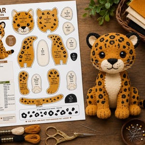 May include: A sewing pattern sheet titled Jaguar Felt Pattern with numbered templates, alongside a finished stuffed felt jaguar toy, embroidery thread, a needle, and scissors. The sheet includes instructions, a materials list, and a pattern pieces list.
