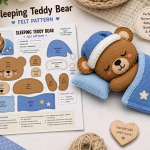 Può includere: Un modello in feltro per un orsacchiotto addormentato, che include un foglio di istruzioni stampato con diagrammi e un orsetto in feltro marrone finito con un berretto da notte blu, poggiato su un cuscino blu sotto una coperta blu con stelle.