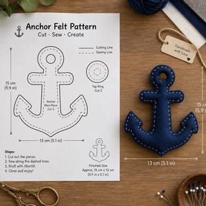 May include: A white paper sheet titled Anchor Felt Pattern with black line drawings, instructions, and measurements of 15 cm by 13 cm. Next to it is a dark blue felt anchor with white stitching, measuring 15 cm by 13 cm, with a tag nearby.