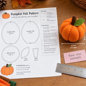Puede incluir: Una hoja de instrucciones Pumpkin Felt Pattern con diagramas de corte y costura, junto a una calabaza de fieltro naranja de 11 cm de ancho por 9 cm de alto, acompañada de una regla metálica para escala y una etiqueta real size example.