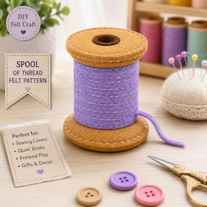 May include: A felt craft spool of thread featuring a purple cylindrical body with white stitched lines and tan circular ends. The spool is accompanied by three small round buttons in purple and tan, a pair of gold scissors, and a pin cushion.