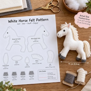 May include: A white horse felt pattern sheet with instructions, a finished white felt horse toy, grey and cream embroidery thread spools, and gold scissors. The finished horse measures 4.7 inches high and 5.9 inches long as indicated by arrows.