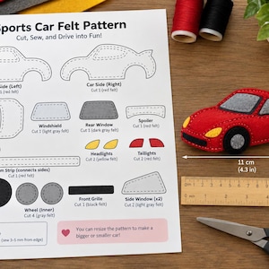 May include: A sports car felt pattern sheet with instructions and a finished red felt car toy measuring 4.3 inches long and 1.8 inches high. The sheet includes outlines for car parts, while a wooden ruler and scissors are placed nearby.