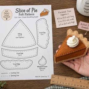 May include: A Slice of Pie felt pattern document with cutting and sewing lines, accompanied by a finished brown felt pie slice with white whipped cream. A note indicates a finished size of 11.5 cm long, 7.5 cm wide, and 6.5 cm high.
