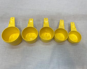 Vintage Tupperware measuring cups, bright yellow measuring utensils, 1 cup, 3/4 cup, 2/3 cup, 1/2 cup, 1/3 cup, 1/4 cup, baking