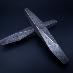 May include: Two silver metal tools with a textured surface, crossed over each other. The tool on top has a small round hole in the center.