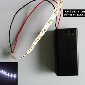 以下が含まれることがあります： 冷白色のLEDストリップ、バッテリーパック、オン/オフスイッチ付き。ストリップは単三電池2本で駆動します。