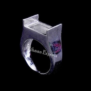 May include: Silver ring setting with a rectangular space for a gemstone. The ring is designed to hold a large stone.