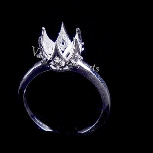 May include: Silver ring setting with a flower-shaped design. The setting is open and ready to hold a gemstone.