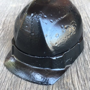May include: A black hard hat with a slightly worn finish. The hat has a rounded top and a brim that extends out to the sides.