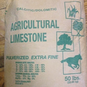 May include: A brown paper bag with green text that reads "Calcitic/Dolomitic Agricultural Limestone Pulverized Extra Fine". The bag also includes a minimum sieve analysis and minimum chemical analysis. The bag is labeled "50 lbs. (22.68 kg)".