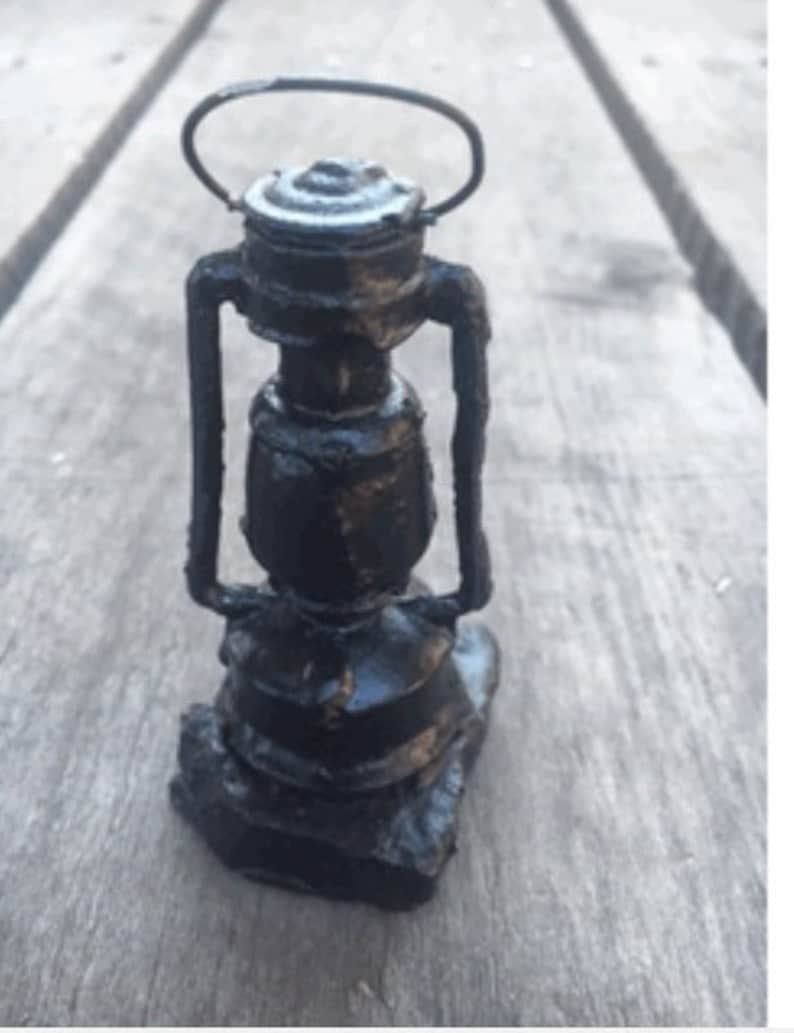 May include: A black metal lantern with a handle and a round glass globe. The lantern is made of a rough, textured metal and has a rustic look.