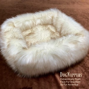 May include: A circular dog bed with a faux fur exterior in cream and light brown hues. The bed features a raised edge and a soft, inviting look. The text "DogNappers" is visible in the image.