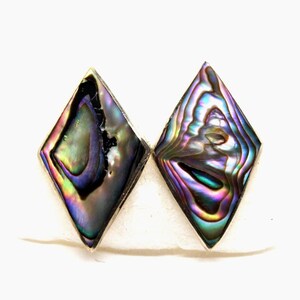 May include: A pair of diamond-shaped earrings with iridescent abalone shell inlays. The earrings display a spectrum of colors, including blues, greens, purples, and hints of gold, set in a silver-toned metal. The abalone shell has a unique, swirling pattern.