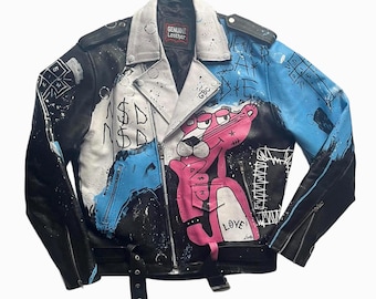 Könnte beinhalten: Schwarze Lederjacke mit weißem Kragen und Gürtel. Die Jacke hat eine rosa Panther-Grafik, blaue und weiße Farbspritzer und die Worte "LOVE" und "NEVER DIE". Die Jacke hat ein "Genuine Leather"-Etikett.