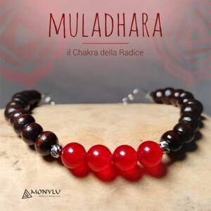 Può includere: Un braccialetto con pietre rosse, perline di legno marrone scuro e dettagli argentati. Il braccialetto è su una superficie di legno. Il testo "MULADHARA il Chakra della Radice" è visibile sullo sfondo.