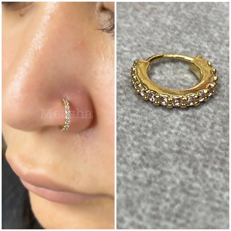 May include: Gold nose ring with a row of clear cubic zirconia stones around the hoop.