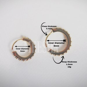 May include: Two gold hoop earrings with a row of clear cubic zirconia stones. The smaller hoop has an inner diameter of 6 mm and the larger hoop has an inner diameter of 8 mm. The hoop thickness is 1.2 mm and the clasp thickness is 0.7 mm.
