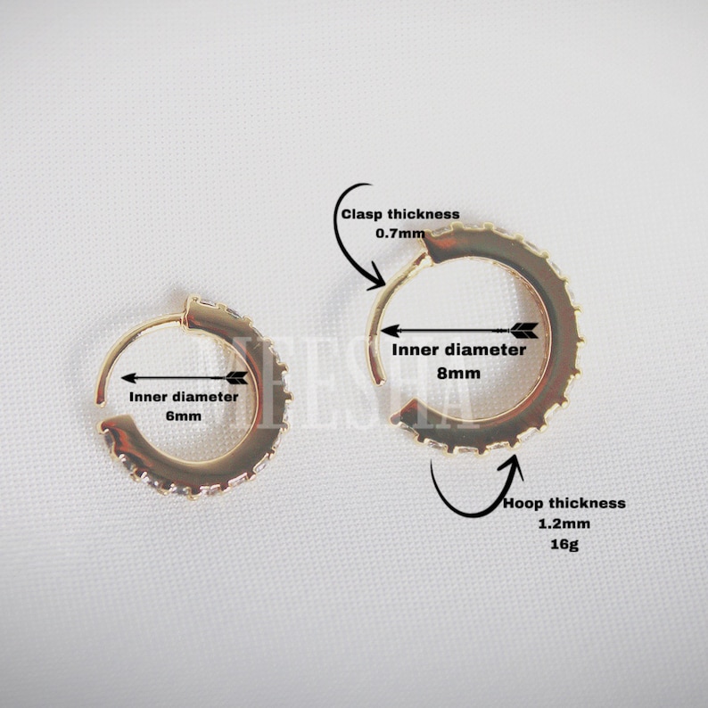 May include: Two gold hoop earrings with a row of clear cubic zirconia stones. The smaller hoop has an inner diameter of 6 mm and the larger hoop has an inner diameter of 8 mm. The hoop thickness is 1.2 mm and the clasp thickness is 0.7 mm.