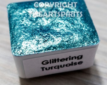 May include: A small square container of turquoise blue glitter paint. The label reads "Copyright TheArtSpirits" and "Glittering Turquoise".