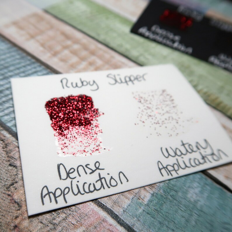 May include: A close-up of two samples of red glitter, labeled "Ruby Slipper". The left sample shows a dense application of glitter, while the right sample shows a watery application.