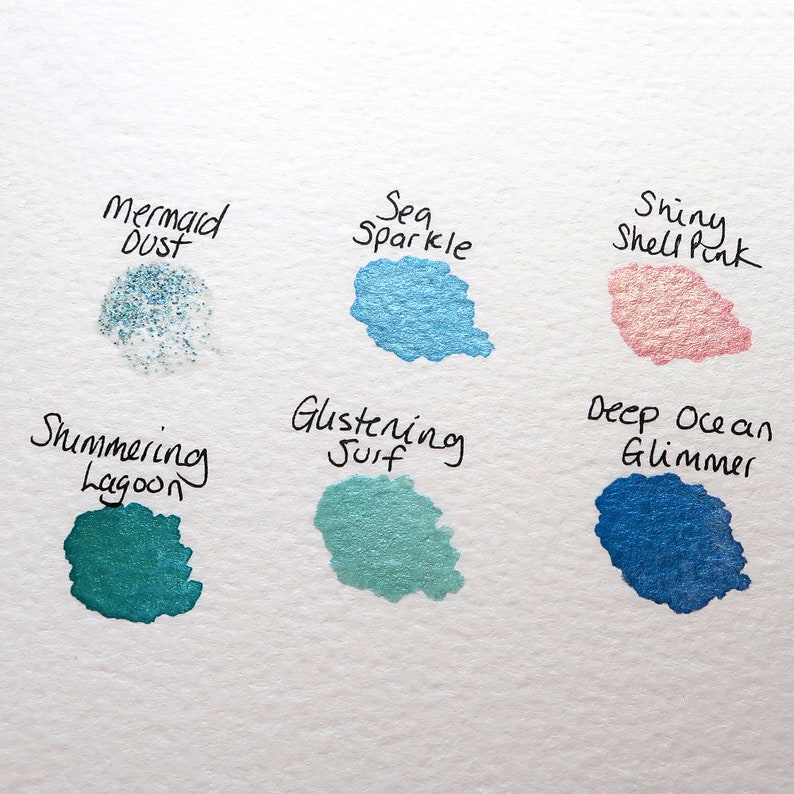 May include: Six different shades of shimmery paint swatches with names written above each one: Mermaid Dust, Sea Sparkle, Shiny Shell Pink, Shimmering Lagoon, Glistening Surf, Deep Ocean Glimmer.