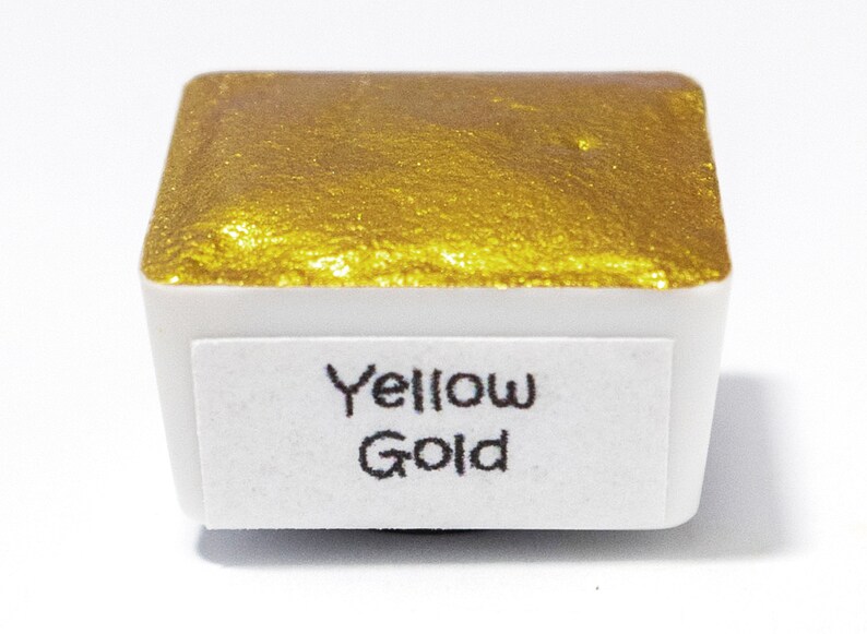 May include: A small, square pan of yellow gold watercolor paint. The pan is labeled "Yellow Gold".