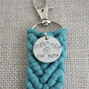 May include: Teal braided keychain with a silver charm that says "mermaid off duty" with a small seashell design.
