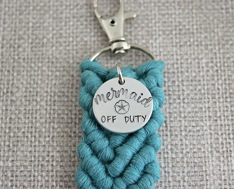 May include: Teal braided keychain with a silver charm that says "mermaid off duty" with a small seashell design.