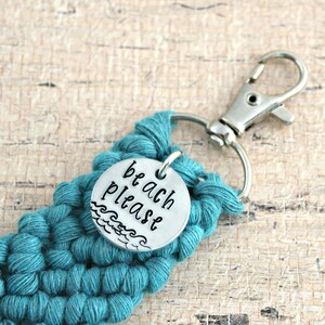 May include: Teal crocheted keychain with a silver charm that says "beach please" with a wave design.