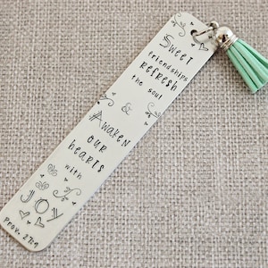 May include: Silver bookmark with a mint green tassel. The bookmark has a quote about sweet friendships refreshing the soul and awakening hearts with joy. The quote is from Proverbs 27:9.