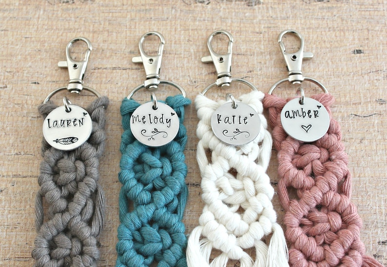 May include: Four crocheted keychains with personalized metal tags. The keychains are in grey, teal, white, and pink. The tags read "Lauren", "Melody", "Katie", and "Amber".