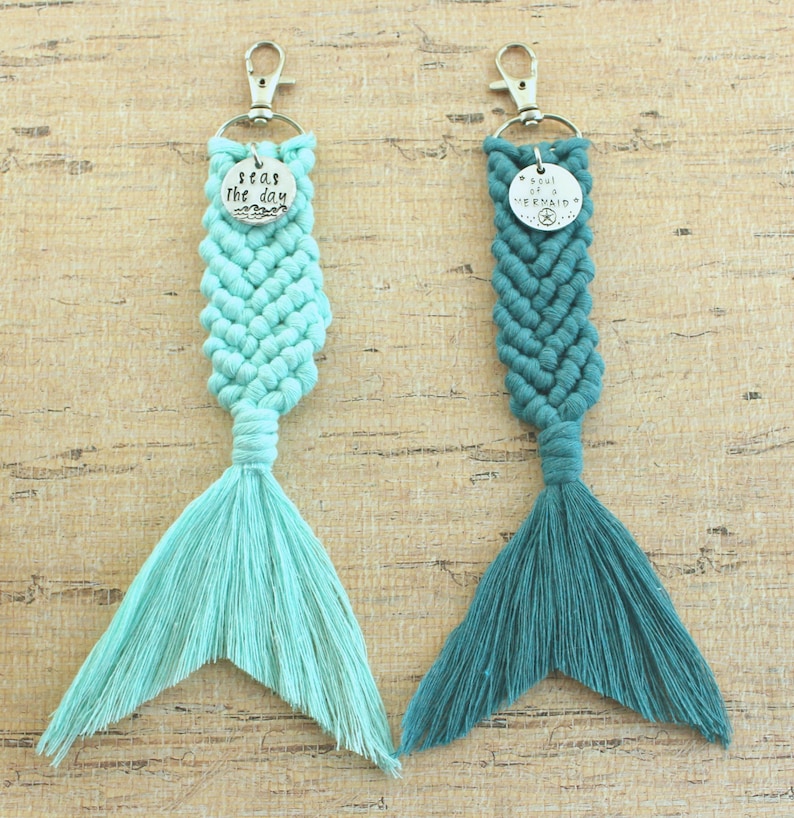 May include: Two mermaid tail keychains with silver charms. One charm says "Seas the day" and the other says "Soul of a Mermaid". The tail on the left is light blue and the tail on the right is teal.