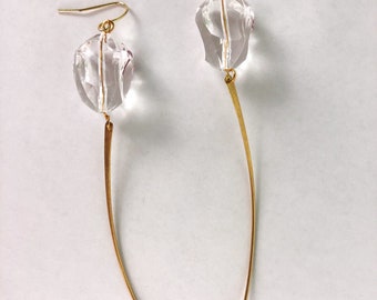 May include: A pair of gold earrings with clear crystal teardrop-shaped pendants. The earrings have long, thin, gold wires.