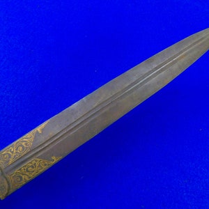 May include: A long, thin, silver-colored dagger with a gold-colored design on the blade. The dagger is sharp and pointed.