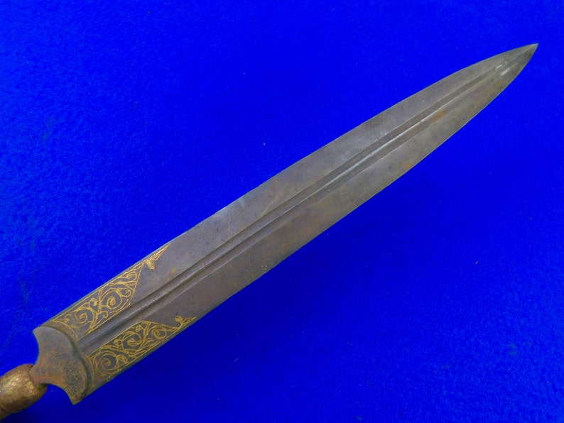 May include: A long, thin, silver-colored dagger with a gold-colored design on the blade. The dagger is sharp and pointed.