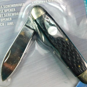 Puede incluir: Un cuchillo de bolsillo con mango negro, hoja plateada y múltiples herramientas. Las herramientas incluyen un destornillador de cruz, un abridor de botellas, un destornillador de ranura, un abrelatas y un punzón/aguja. El cuchillo está empaquetado en un blíster de plástico transparente.