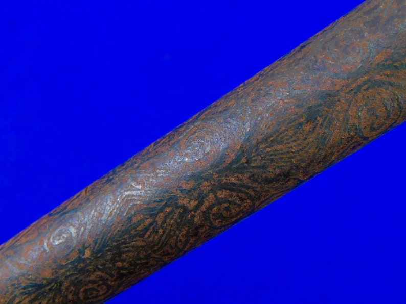 May include: Close-up of a long, dark brown metal rod with a swirling, textured pattern. The rod has a slightly rough surface and a dark, almost black, color.