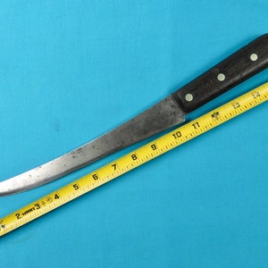 May include: A long, curved, silver-colored knife with a black wooden handle and a yellow measuring tape. The knife is approximately 14 inches long.