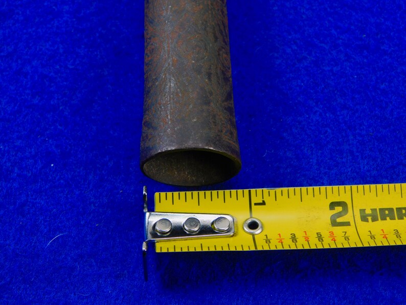 May include: Close-up of a rusty metal pipe with a diameter of 2 inches, measured with a yellow tape measure.